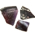 Three pieces of dark purple, broken glass with some white and orange marks on the top right hand piece.