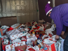 Ben with CW van Community engagement officer standing in van full of Christmas presents