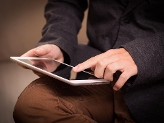 A man's hand pointing to something on his tablet computer