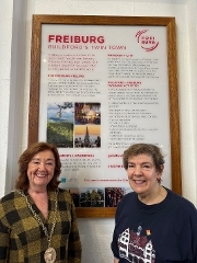 The Mayor of Guildford, Cllr Sallie Barker MBE and Chair of Guildford Twinning, Barbara Ford infront of Freiburg poster at Tunsgate