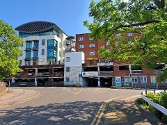 Bedford Road Car Park June 2023 Mixed-style building with car park entrance and tree in foreground.