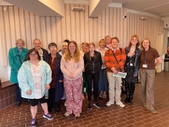 A group of people smiling at the camera inside the Yvonne Arnaud Theatre