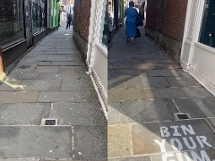 Side-by-side before-and-after photographs of a narrow paved alleyway between brick buildings and shopfronts. The image on the left shows paving stones marked with small white chewing gum stains. The image on the right shows the same alleyway after cleanin